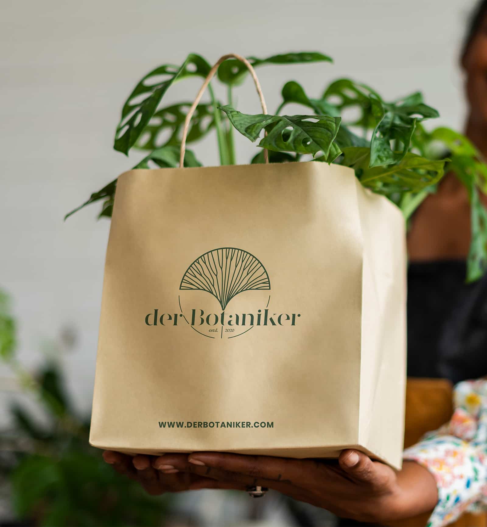 Umweltfreundliche Tragetasche mit dem Logo von DerBotaniker, gehalten von einem Kunden, repräsentiert das Engagement der Marke für Nachhaltigkeit und Stil.